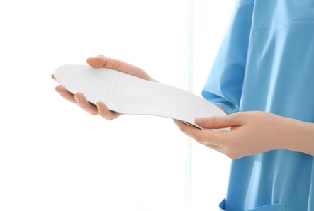 Female orthopedist with insole on white background, closeup